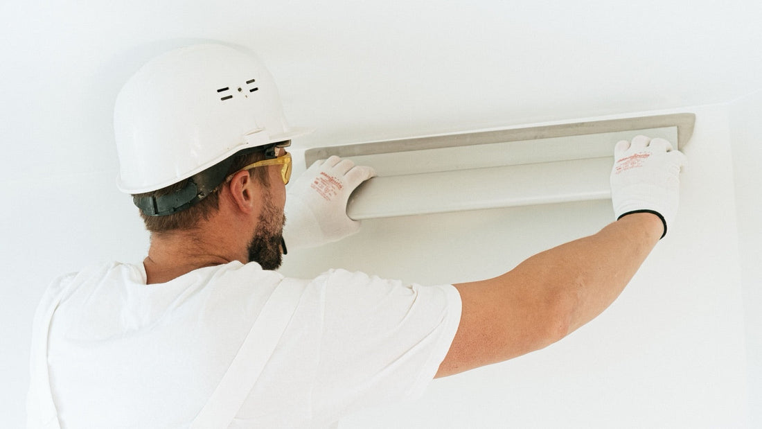 DIY ceiling cassette mini split easy install - installer in hard hat fitting a recessed ceiling cassette air handler panel overhead