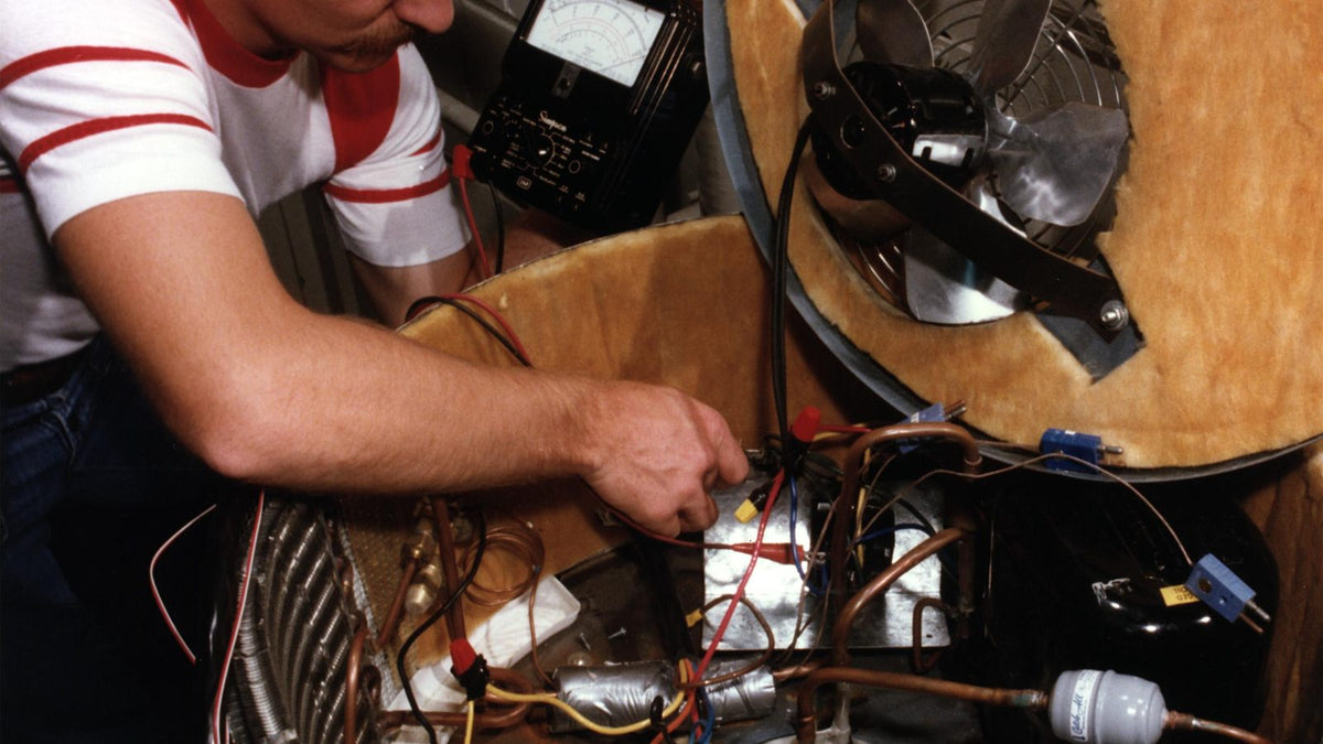 Technician uses multimeter on HVAC system with copper tubing to check refrigerant level home ac mini split components