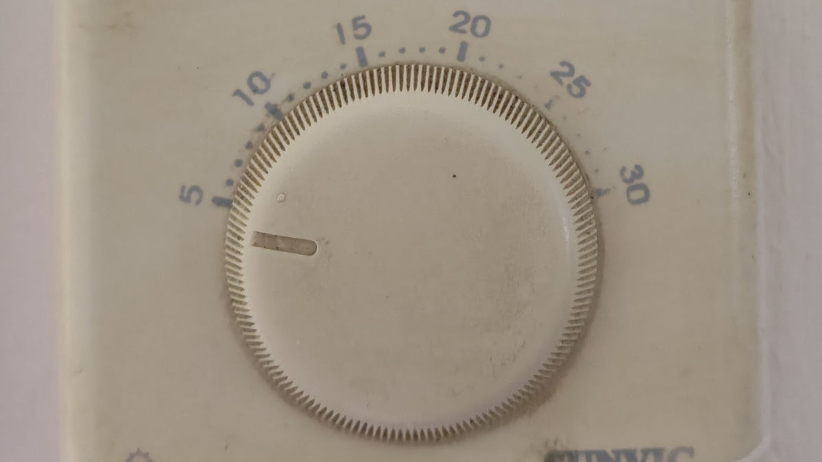 Wall-mounted Sunvic electronic thermostat with circular temperature dial showing 5 to 30 degrees Celsius, replace a thermostat guide example