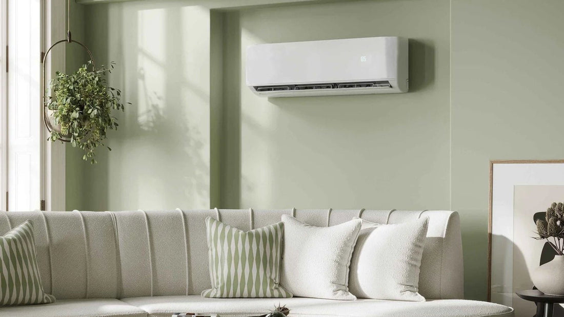 White wall-mount mini split indoor unit above a sofa in a sage green living room, one head of a DIY dual zone mini split system