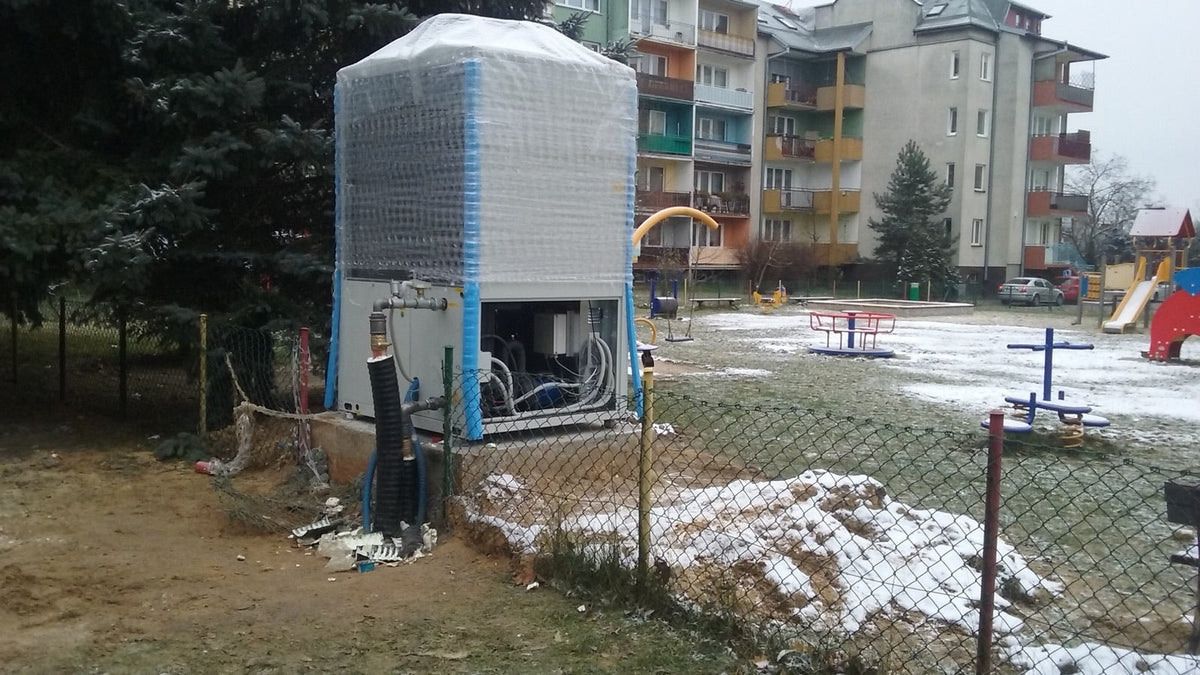 Outdoor heat pump unit wrapped for winter beside a snowy yard, the kind of cold weather a MRCOOL Universal or DIY 4th Gen has to heat through